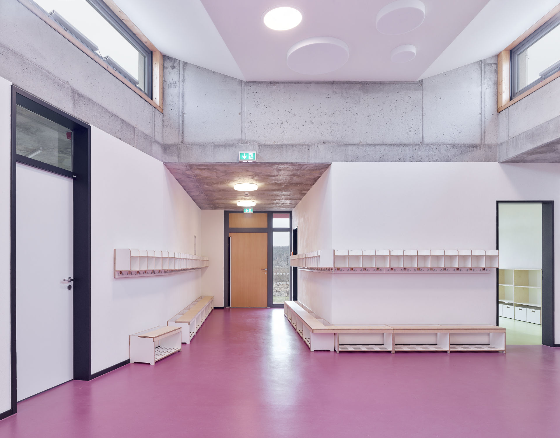 Garderoben mit Bänken; verschiedenen Materialisten und Farben an Decke, Boden und Wand; Blick zu Ausgang