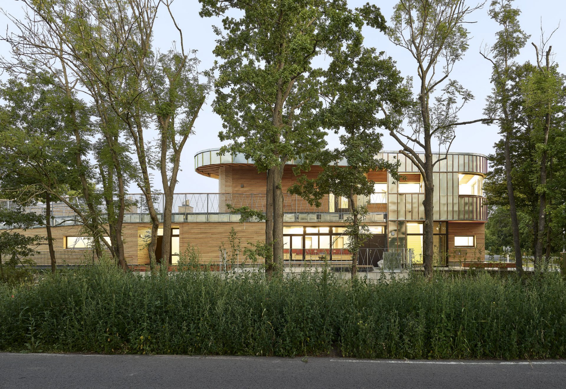 Kita mit Holz- und Metallfassade hinter Bäumen