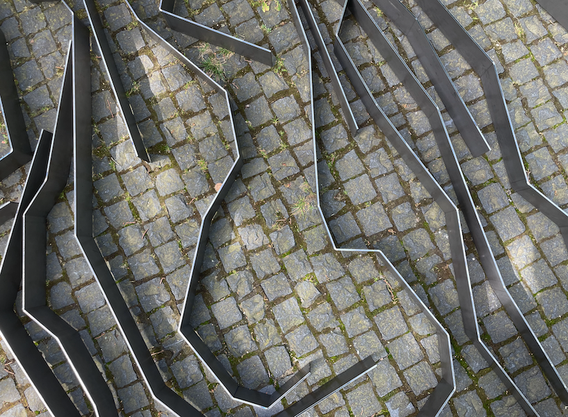 geknickte Erdliner aus Schwarzstahl auf Pflastersteinen