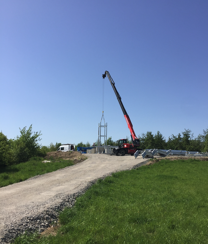 Baustelle: Stahlelemente an Kran auf Hügel