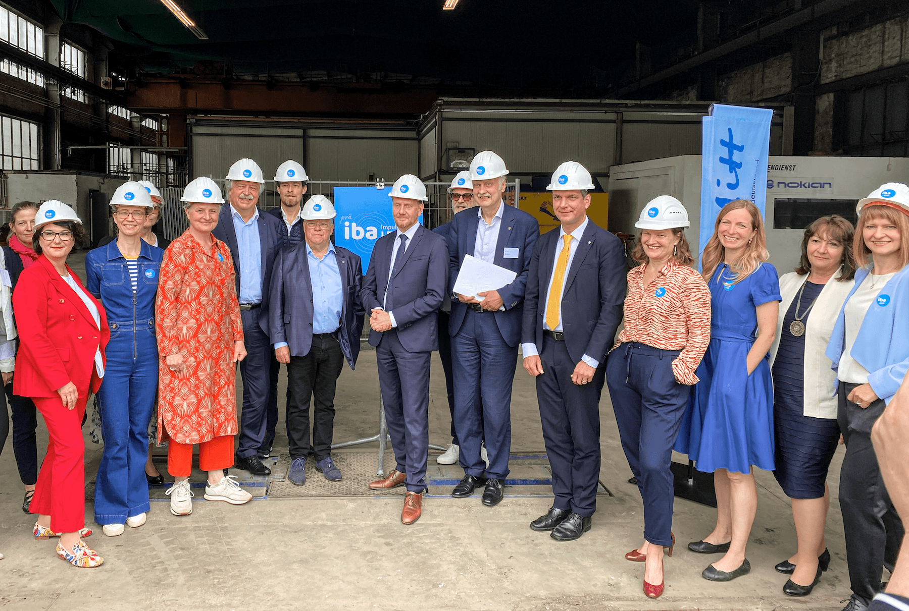 Gruppenfoto: Menschen mit Baustellenhelmen bei der Übergabe des Förderantrags mit Ministerpräsident Michael Kretschmer